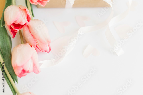 Fototapeta Naklejka Na Ścianę i Meble -  Pink tulips with ribbon on white background with gift box. Stylish tender image. Happy womens day. Greeting card with space for text. Happy Mothers day. Wedding or valentine celebration