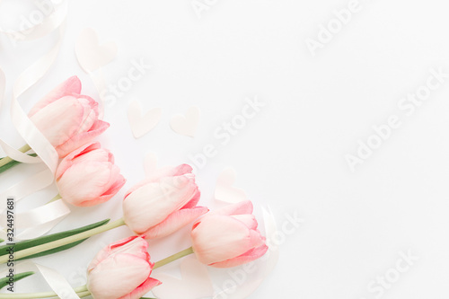 Pink tulips with ribbon and hearts on white background, flat lay. Stylish soft spring image. Happy womens day. Greeting card mockup with space for text. Happy Mothers day. Hello spring © sonyachny