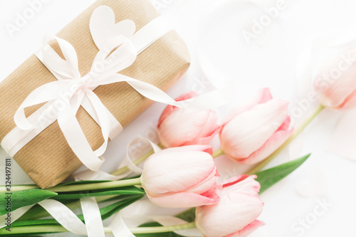 Pink tulips flat lay with ribbon and gift box on white background. Stylish soft image of spring flowers. Happy womens day. Greeting card mockup. Happy Mothers day. Hello spring