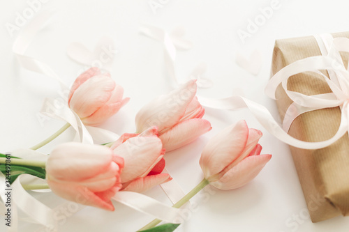 Fototapeta Naklejka Na Ścianę i Meble -  Pink tulips with ribbon and gift box on white background. Stylish soft image of spring flowers. Happy womens day. Greeting card mockup. Happy Mothers day. Hello spring