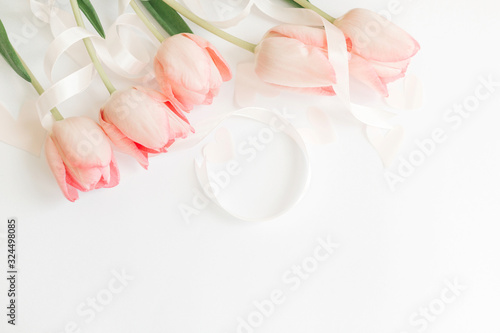 Hello spring. Pink tulips with ribbon and hearts on white background  flat lay. Stylish soft spring image. Happy womens day. Greeting card mockup with space for text. Happy Mothers day.