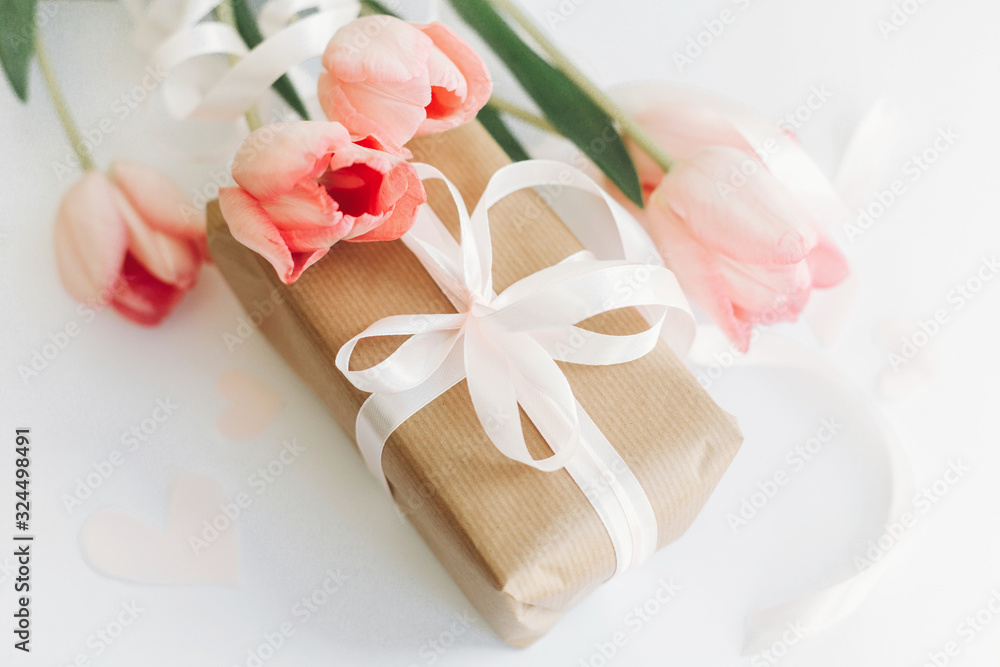 Happy Mothers day. Pink tulips with ribbon and gift box on white background. Stylish soft image of spring flowers. Happy womens day. Greeting card mockup. Hello spring Happy Mothers day. Pink tulips with ribbon and gift box on white background. Stylish soft image of spring flowers. Happy womens day. Greeting card mockup. Hello spring