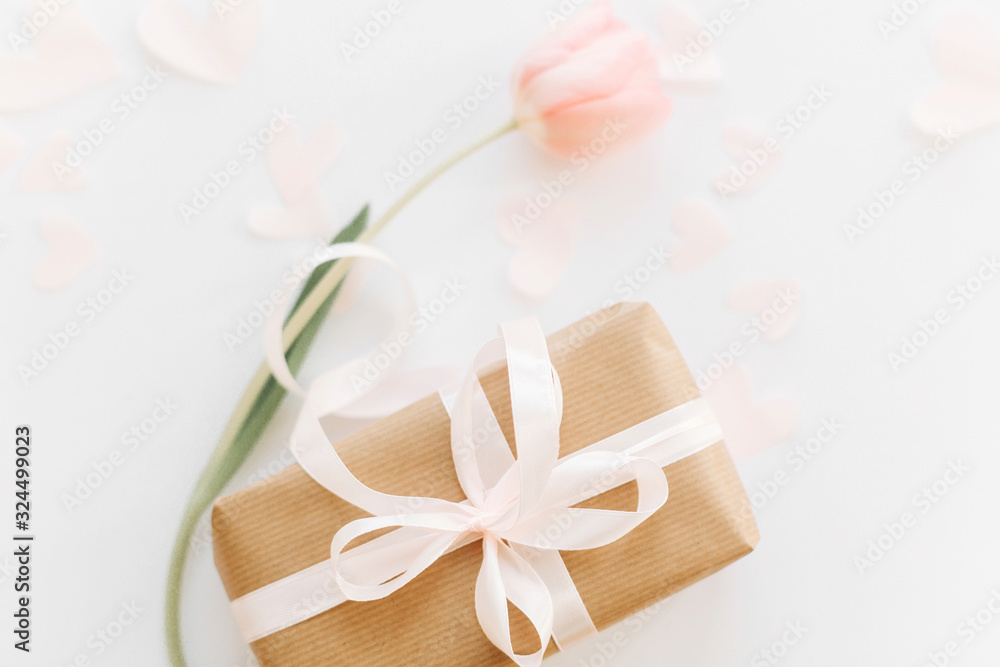 Gift box with ribbon and pink tulip flat lay on white background, space for text. Stylish soft spring image. Happy womens day. Greeting card mockup. Happy Mothers day. Romantic Valentines day Gift box with ribbon and pink tulip flat lay on white background, space for text. Stylish soft spring image. Happy womens day. Greeting card mockup. Happy Mothers day. Romantic Valentines day