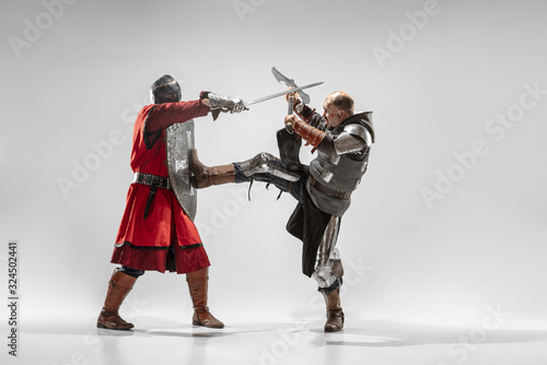 Brave armored knights with professional weapon fighting isolated on white studio background. Historical reconstruction of native fight of warriors. Concept of history, hobby, antique military art.
