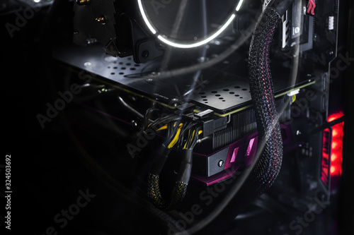 Close-up video card with backlight inside a computer on a black background. The concept of computer games, cyber sports and computer repair. Banner format, wallpapers.