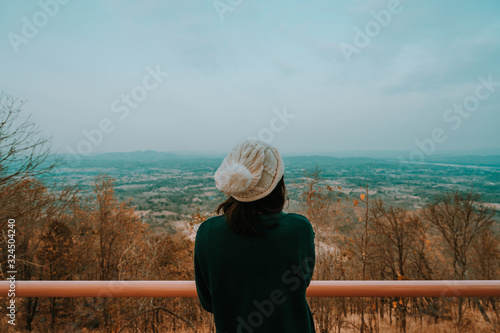 A woman looking over a landscape and yellow tree  at phu-thok thailand. orange and teal tone