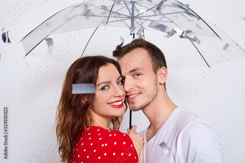 Young couple in love embracing under confetti in decorated studio. photo