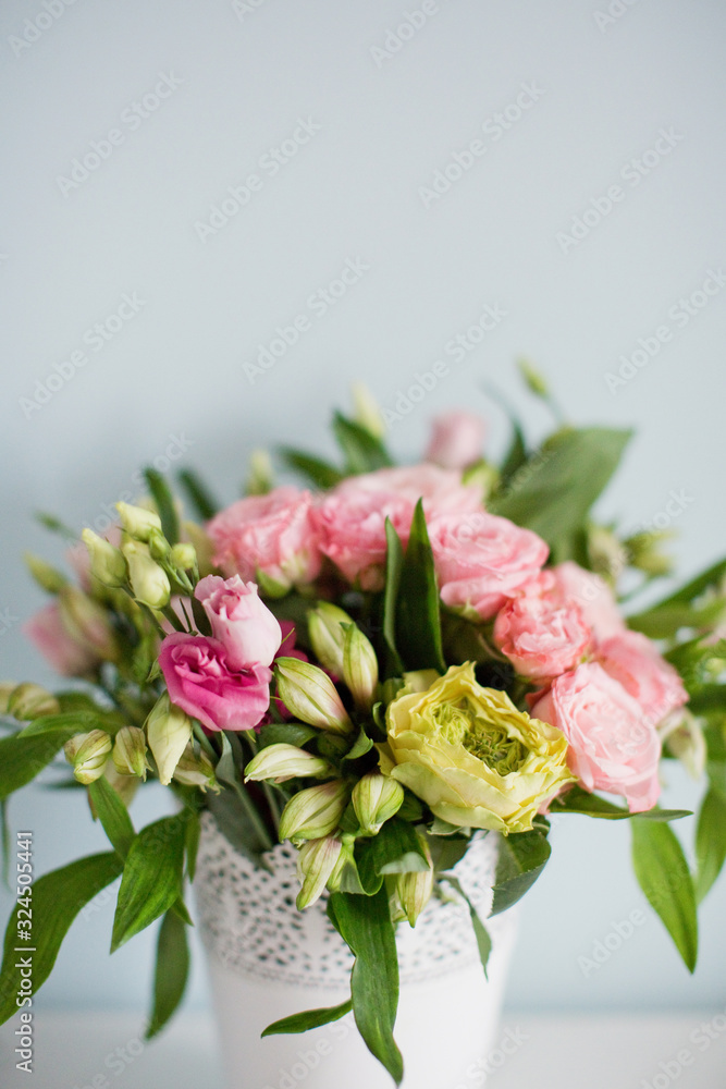 Bright bouquet with roses, eustoma and alstroemeria in white vase. Bouquet on soft blue background Bright bouquet with roses, eustoma and alstroemeria in white vase. Bouquet on soft blue background