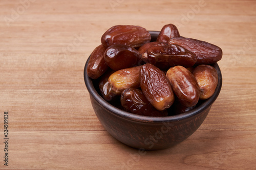 dried date fruit in bowl on wooden table background.