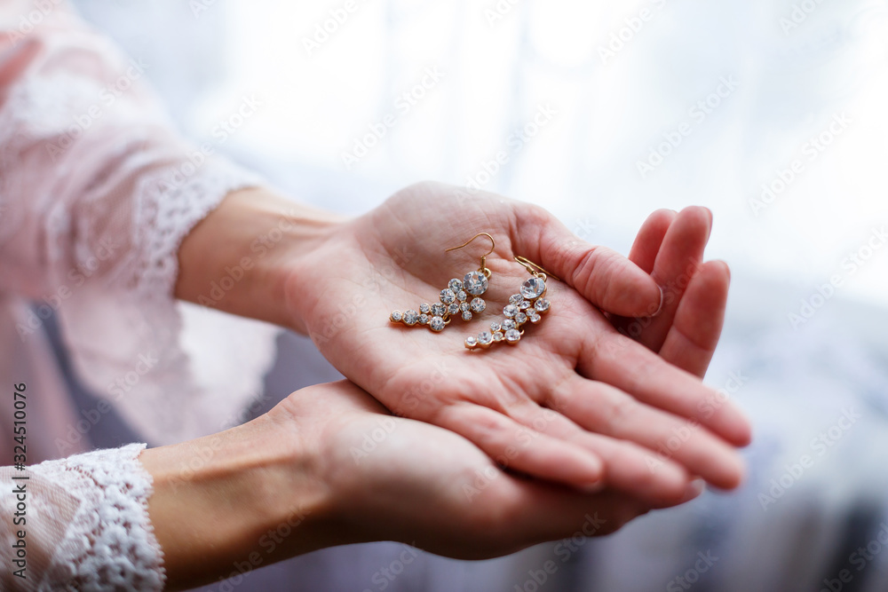girl in a beautiful white dress holds earrings in her hands