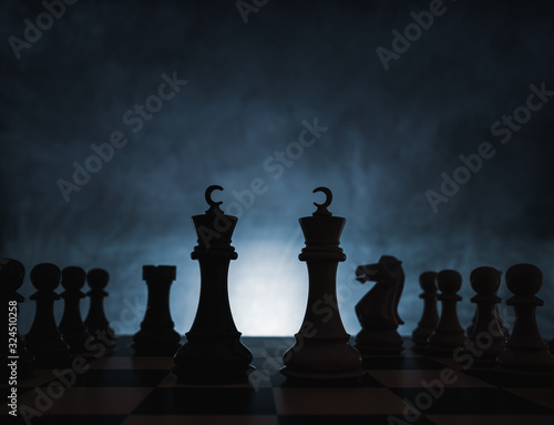 Chess game concept of challenge, ideas and competition. Chess figures isolated with dark background with fog and white light.