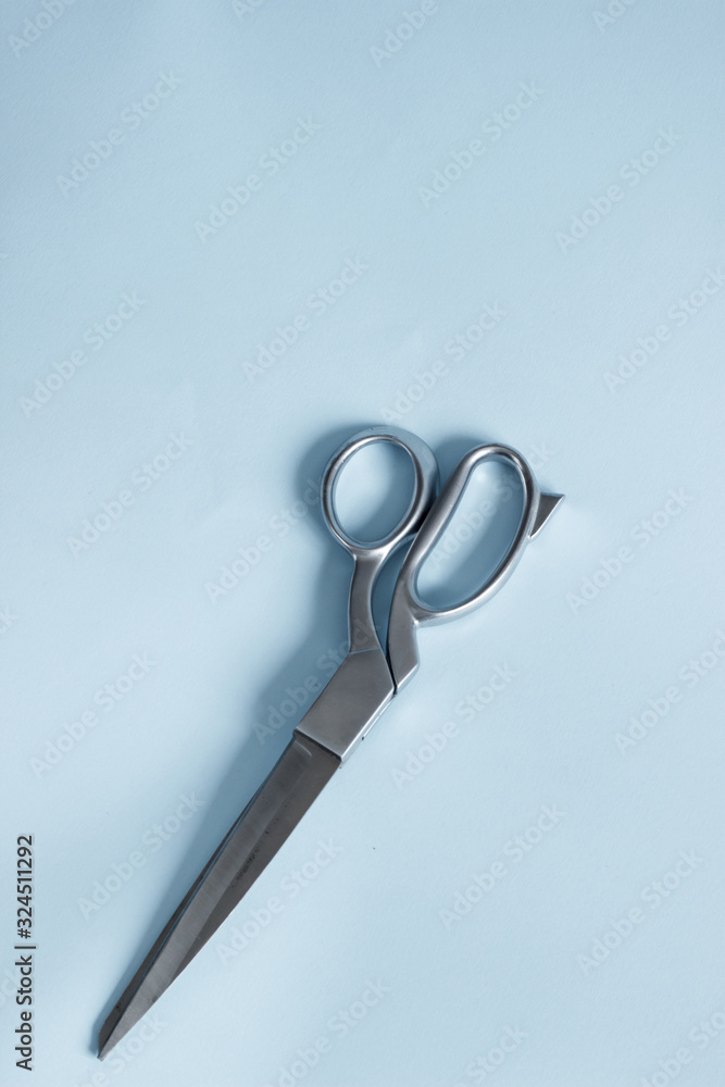 Silver scissors with pink white violet sewing threads on blue pastel background Silver scissors with pink white violet sewing threads on blue pastel background