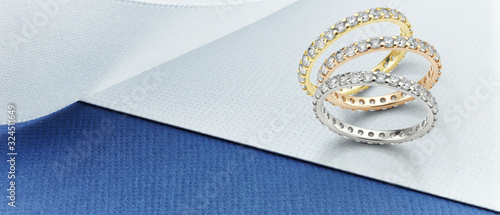 Eternity Rings on Blue and White Background. Featuring White Gold, Yellow Gold and Rose Gold diamond eternity ring banner on blue and white card. 