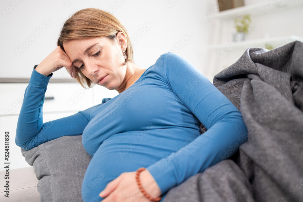 Pregnant tired exhausted woman with stomach and head issues at home on a couch, being sick. Pregnant tired exhausted woman with stomach and head issues at home on a couch, being sick.