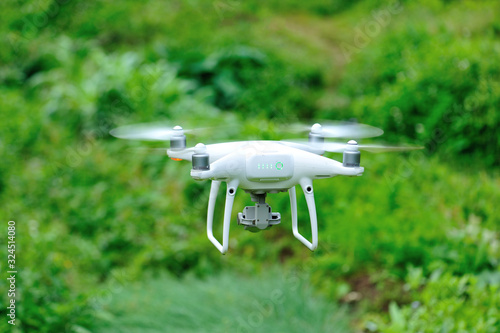 White drone with camera flying in the spring countryside