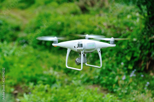 White drone with camera flying in the spring countryside