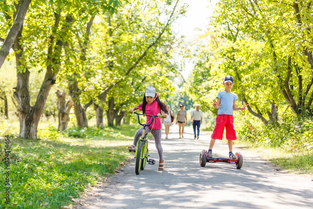 Girl on a bicycle and a boy on a gyroscope are riding together