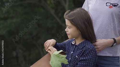Beautiful little girl with blue eyes in a blue dress on a walk in the park