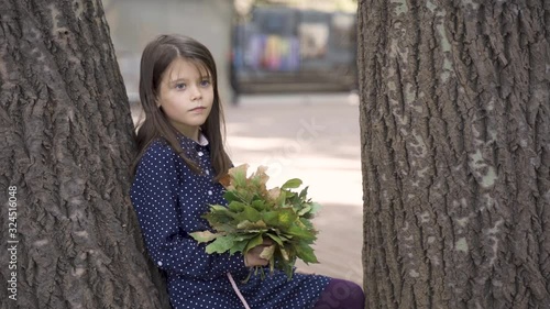 Beautiful little girl with blue eyes in a blue dress on a walk in the park