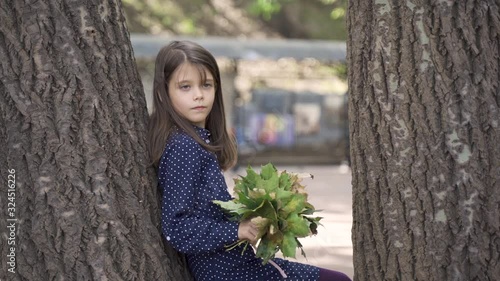 Beautiful little girl with blue eyes in a blue dress on a walk in the park