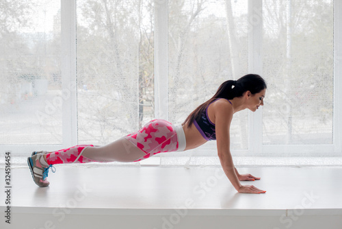 Athletic young girl performs exercises in the Studio on a light background. Fitness  healthy lifestyle