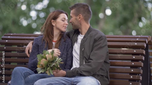 Beautiful couple kisses on a bench in the park, a romantic date