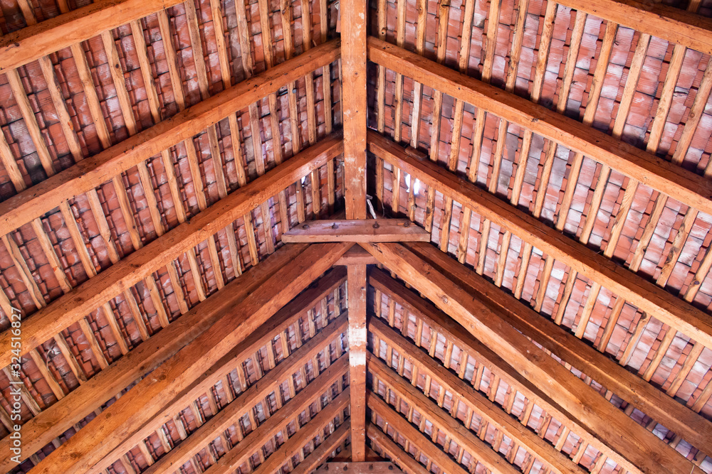 Wooden roof ridge in a old attic with view of the roof shingles