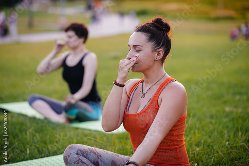 Fototapeta Naklejka Na Ścianę i Meble -  Young girls do yoga outdoors in the Park during sunset. Healthy lifestyle