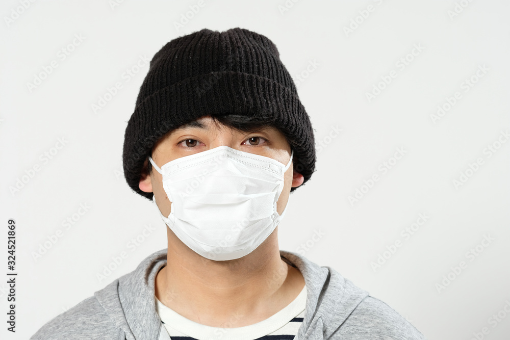 感染症予防の為に衛生マスクをしてニット帽をかぶってる日本人男性のバストアップ正面 Stock Photo Adobe Stock
