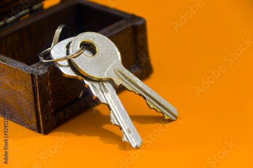 Small treasure box and key on orange background         