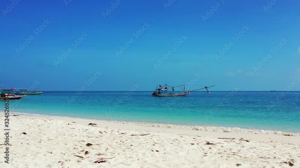 Long tail boats anchoring on calm turquoise lagoon near white sandy beach of tropical island, bright blue sky in Thailand Long tail boats anchoring on calm turquoise lagoon near white sandy beach of tropical island, bright blue sky in Thailand