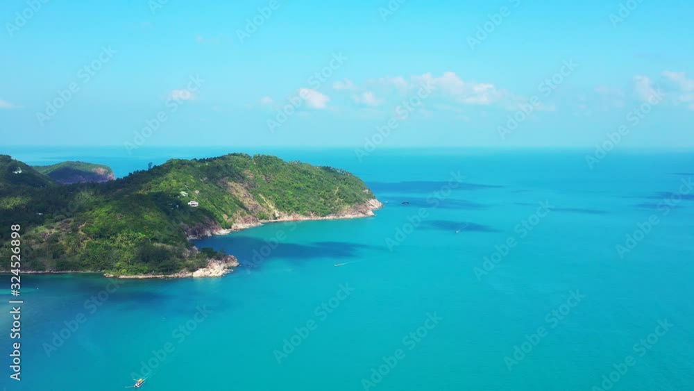 Paradise tropical island coastline with rocks and lush vegetation washed by calm clear azure sea under bright blue sky, Thailand Paradise tropical island coastline with rocks and lush vegetation washed by calm clear azure sea under bright blue sky, Thailand
