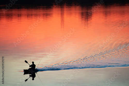 Rowing a canoe in lake samsonvale with beautiful red sunset reflections and a trail of ripples behind photo