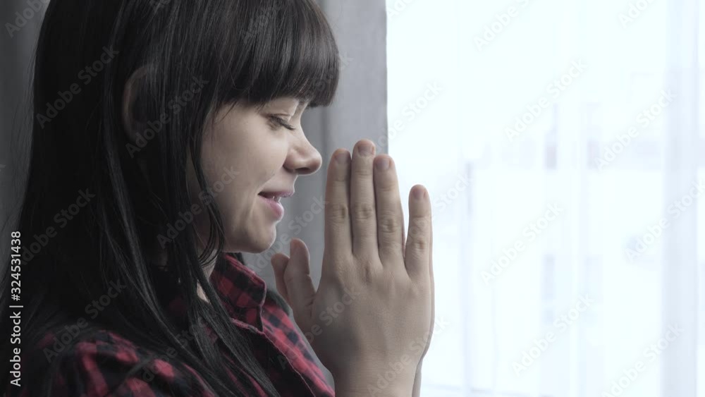 brunette girl makes a wish prayers bedtime religion concept. prayer woman mom indoors praying by bed front of lifestyle window brunette girl makes a wish prayers bedtime religion concept. prayer woman mom indoors praying by bed front of lifestyle window