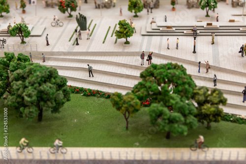 Miniature people figurines at modern city square.