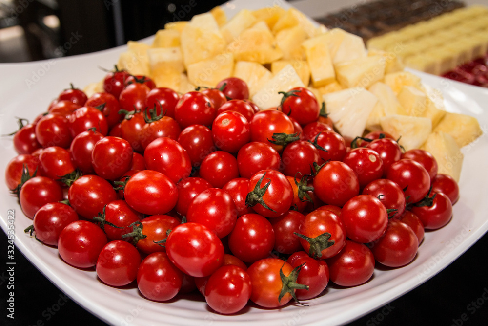 A lot of cherry tomatoes and slice pineapple on a large bowl. A lot of cherry tomatoes and slice pineapple on a large bowl.