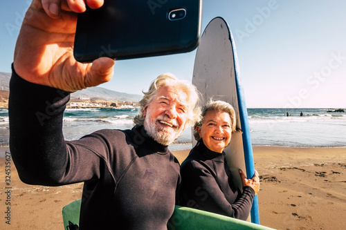 Photography couple of pensioners seniors taking a selfie together at the beach with their we