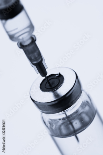 Ampoules for injection. Glass medical vials for vaccination. Transparent bottles and disposable syringe on a white background. Antibiotic for treating the virus.