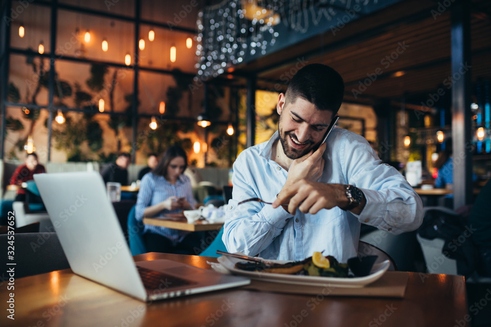 young businessman having lunch and using laptop in restaurant young businessman having lunch and using laptop in restaurant
