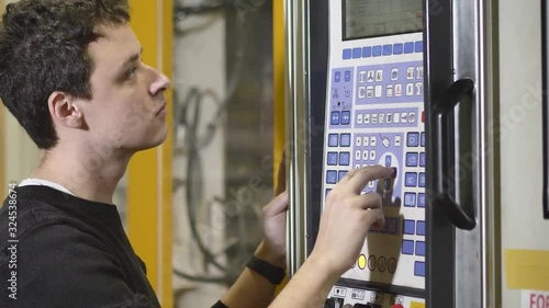 Production Worker / Machine Adjuster Adjusts the Automatic Injection Molding Machine to Start Production of Molding Housing for the Headlamps in Automotive Factory