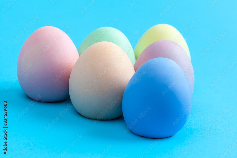 Extreme closeup of Easter eggs painted in plain colors on blue background with copy space Extreme closeup of Easter eggs painted in plain colors on blue background with copy space