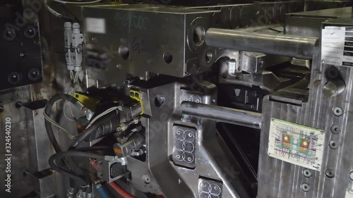 Automatic Plastic Injection Molding Machine, Robotics Arm Removes the Finished Headlamps Housing from the Injection Mold and Put it on the Conveyor Belt in Automotive Factory