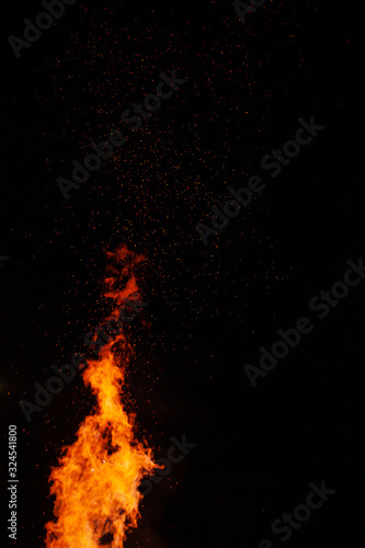 Fire flames on a dark background with lots of fiery sparks from a blazing fire