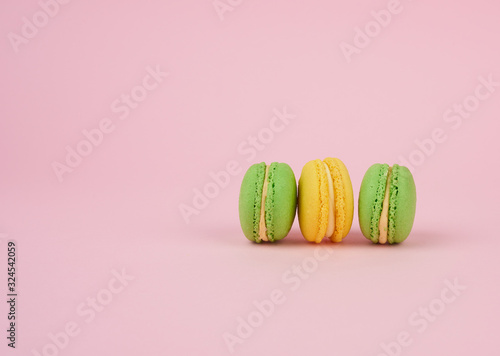 green and yellow round baked macarons on a pink background