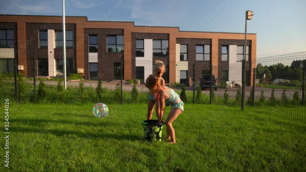 Cute sisters girls splashing water on each other with water shotguns in yard Cute sisters girls splashing water on each other with water shotguns in yard