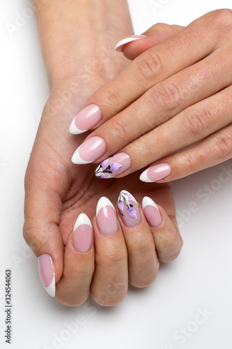 French manicure with painted flowers on sharp long nails closeup on a white background.