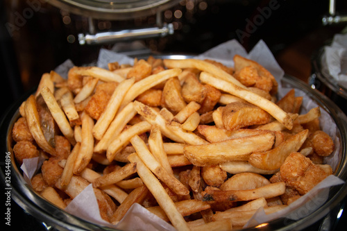 French fries and deep fried potato wedges mixed in a large buffet tray.