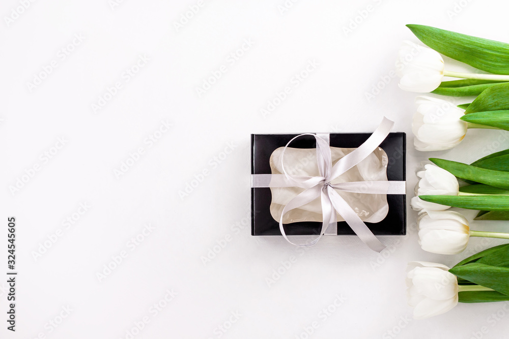 Spring website header template. White tulip black gift box with silver ribbon on light background flat lay. Text place 8 March Happy Mothers Day Sales.Bouquet greeting card. Copy space banner top view Spring website header template. White tulip black gift box with silver ribbon on light background flat lay. Text place 8 March Happy Mothers Day Sales.Bouquet greeting card. Copy space banner top view