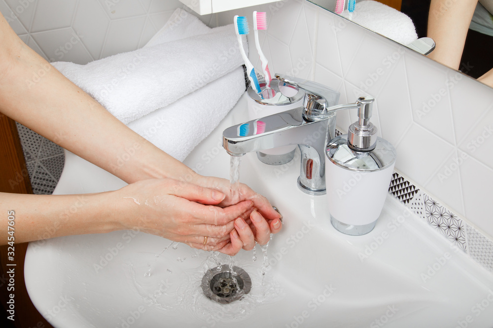 Everyday morning hygiene. Woman wash her hands. Bath preparation. White interior of bathroom. Toothbrush and soap dispenser. Details of bathroom. Personal care. Measures against infection and virus Everyday morning hygiene. Woman wash her hands. Bath preparation. White interior of bathroom. Toothbrush and soap dispenser. Details of bathroom. Personal care. Measures against infection and virus