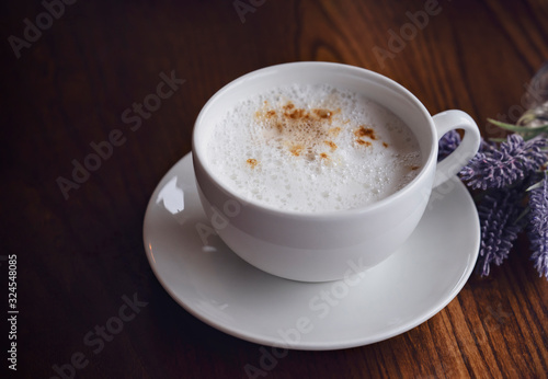 White cup of hot coffee latte on wooden table background. Top view coffee on table with dark light in afternoon